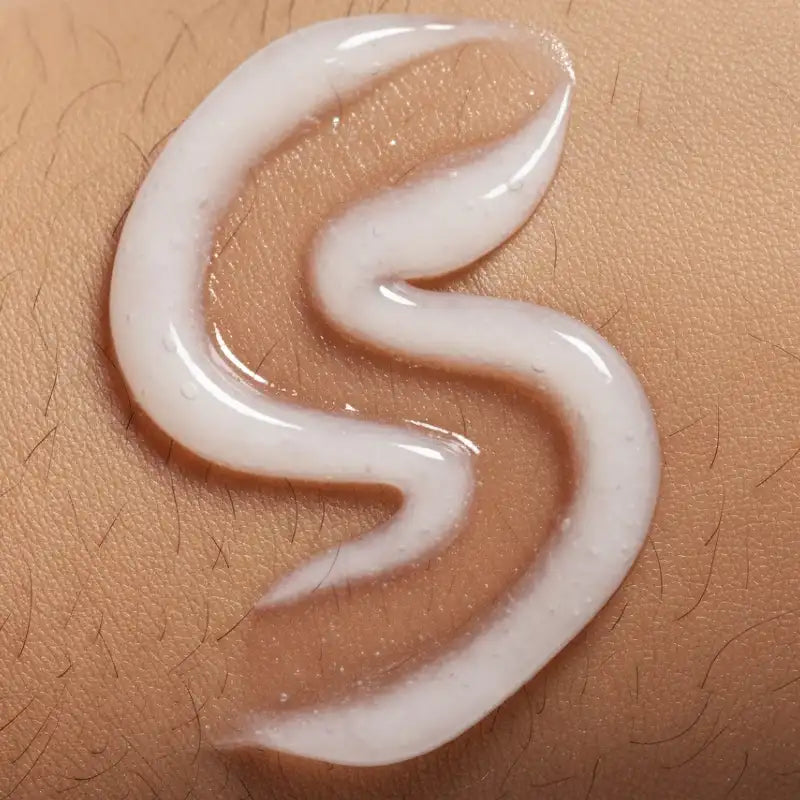White cream or lotion in a curved line on beige skin