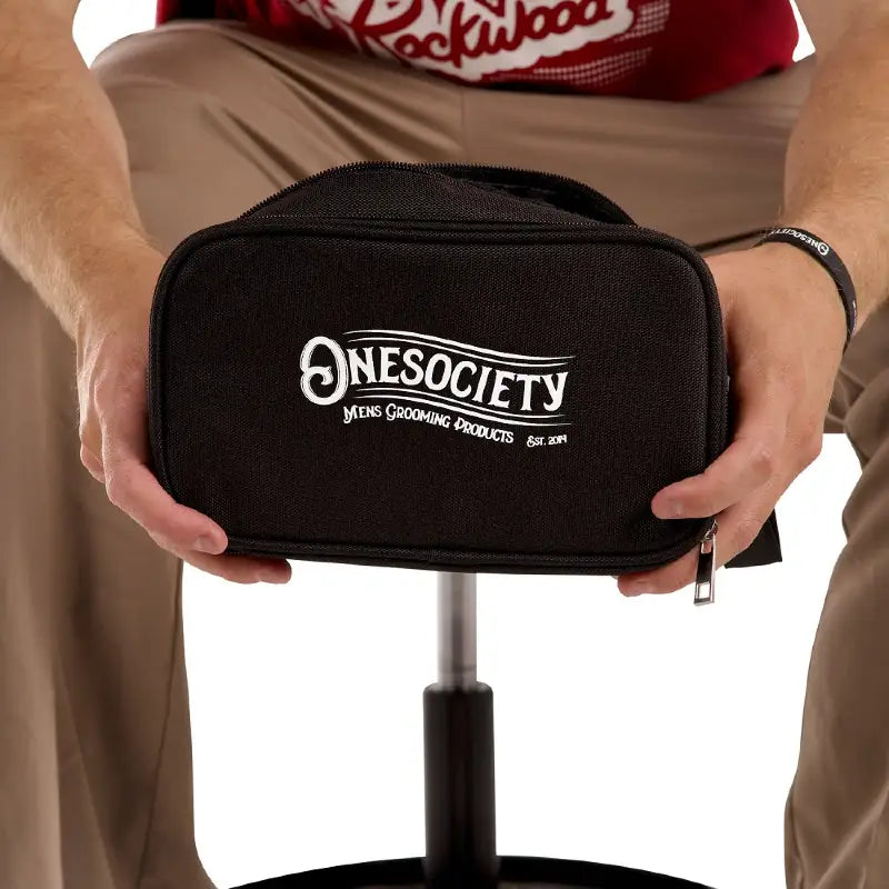 Man holding one society gym wash bag while sitting down
