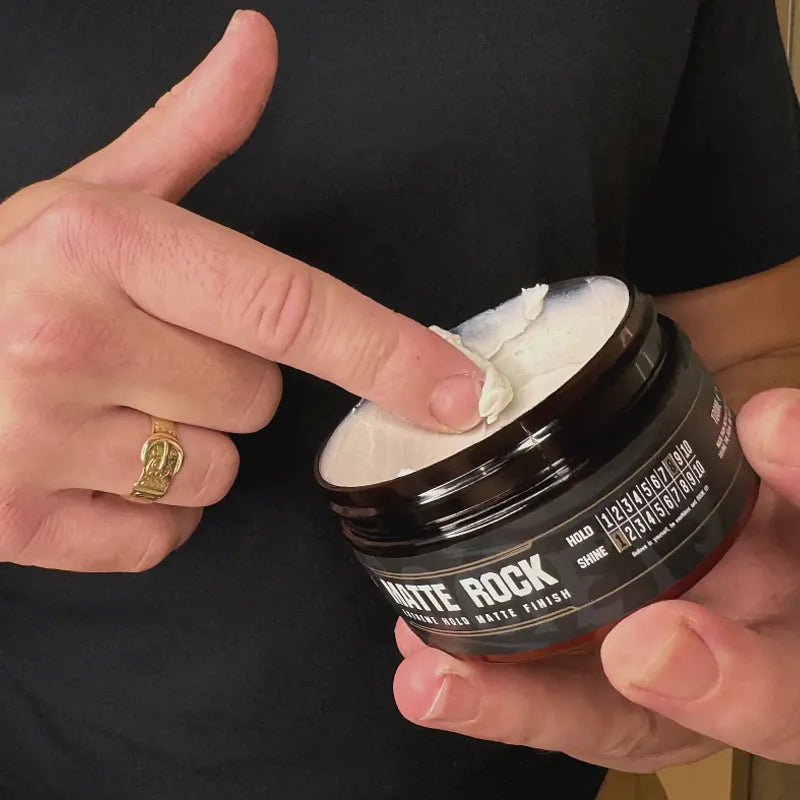 Person holding a jar of matte rock product with a finger going in