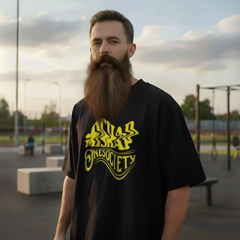 Man wearing a black t-shirt with yellow graphics in an outdoor setting