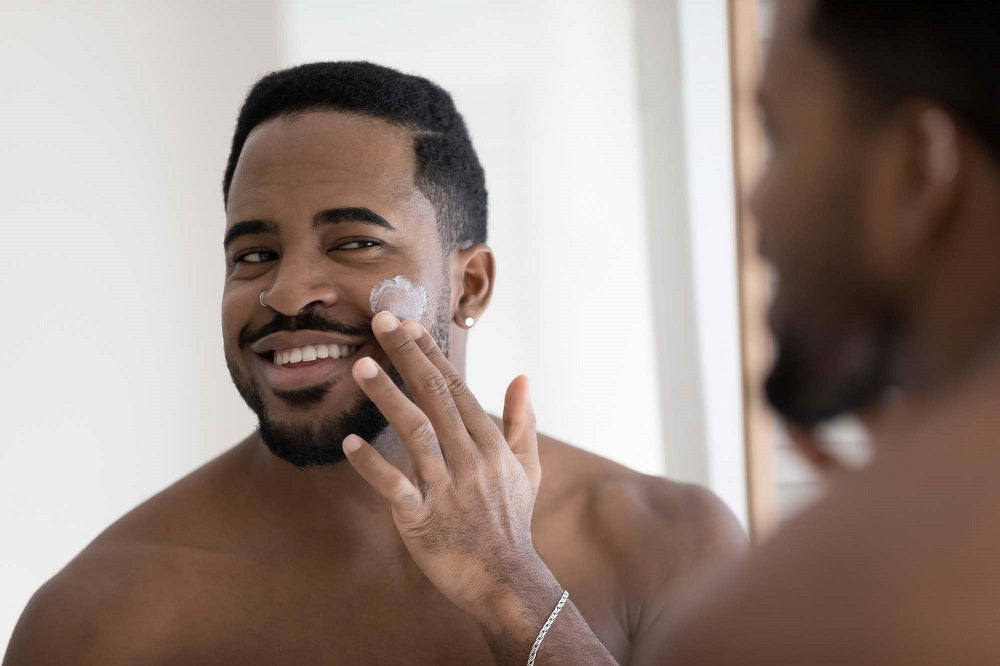 Black man using cream for a good self care routine