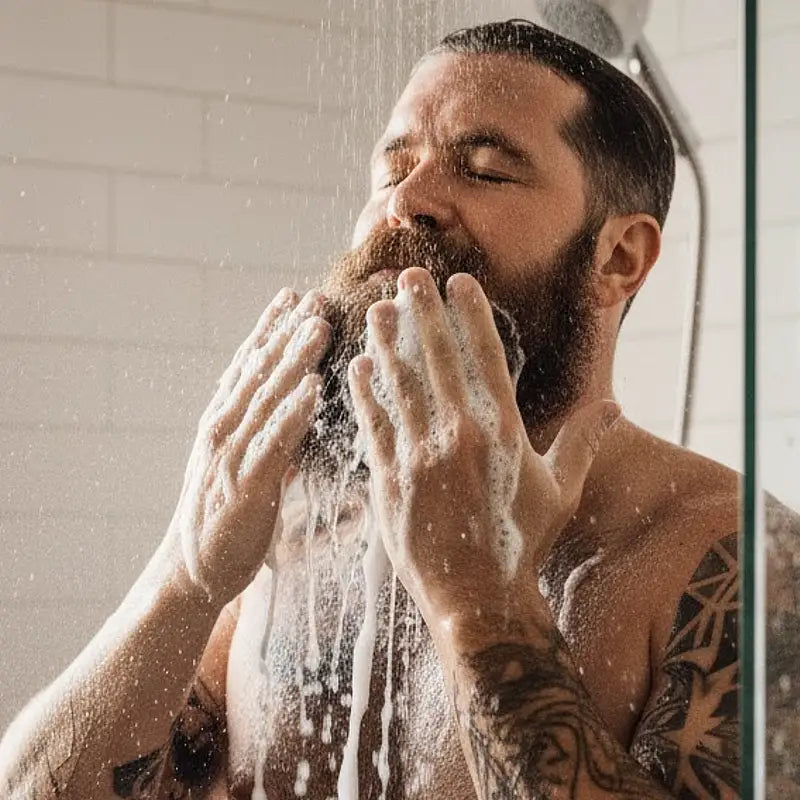 one society beard shampoo being used on a mans beard in the shower