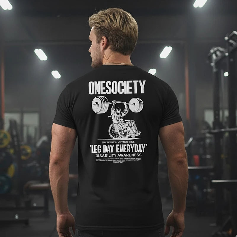 Person wearing a black t-shirt with 'ONESOCIETY' and 'Leg Day Everyday' design in a gym setting.