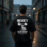 Person wearing a black t-shirt with 'ONESOCIETY' design and text on a city street.