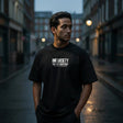 Man wearing a black t-shirt with 'ONESOCIETY' text on a city street.