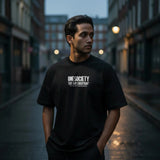 Man wearing a black t-shirt with 'ONESOCIETY' text on a city street.