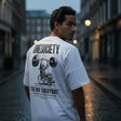 Man wearing a white t-shirt with 'ONESOCIETY' and 'LEG DAY EVERYDAY' design on a city street.