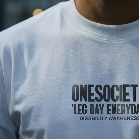 Person wearing a light gray sweatshirt with 'ONESOCIETY LEG DAY EVERYDAY DISABILITY AWARENESS' text.