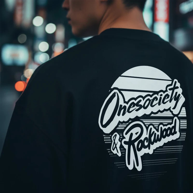 Person wearing a black sweatshirt with 'Onesociety & Rockwood' logo in an urban setting