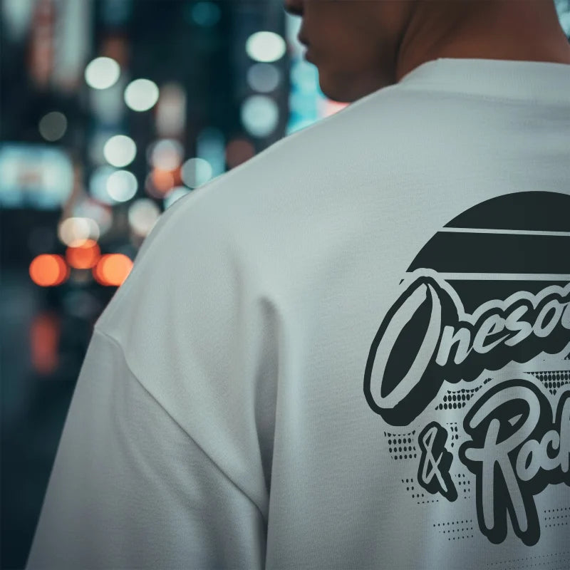 Person wearing a white t-shirt with a brand logo on the back against a blurred cityscape background