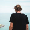 Person wearing a black t-shirt standing on a beach with ocean view
