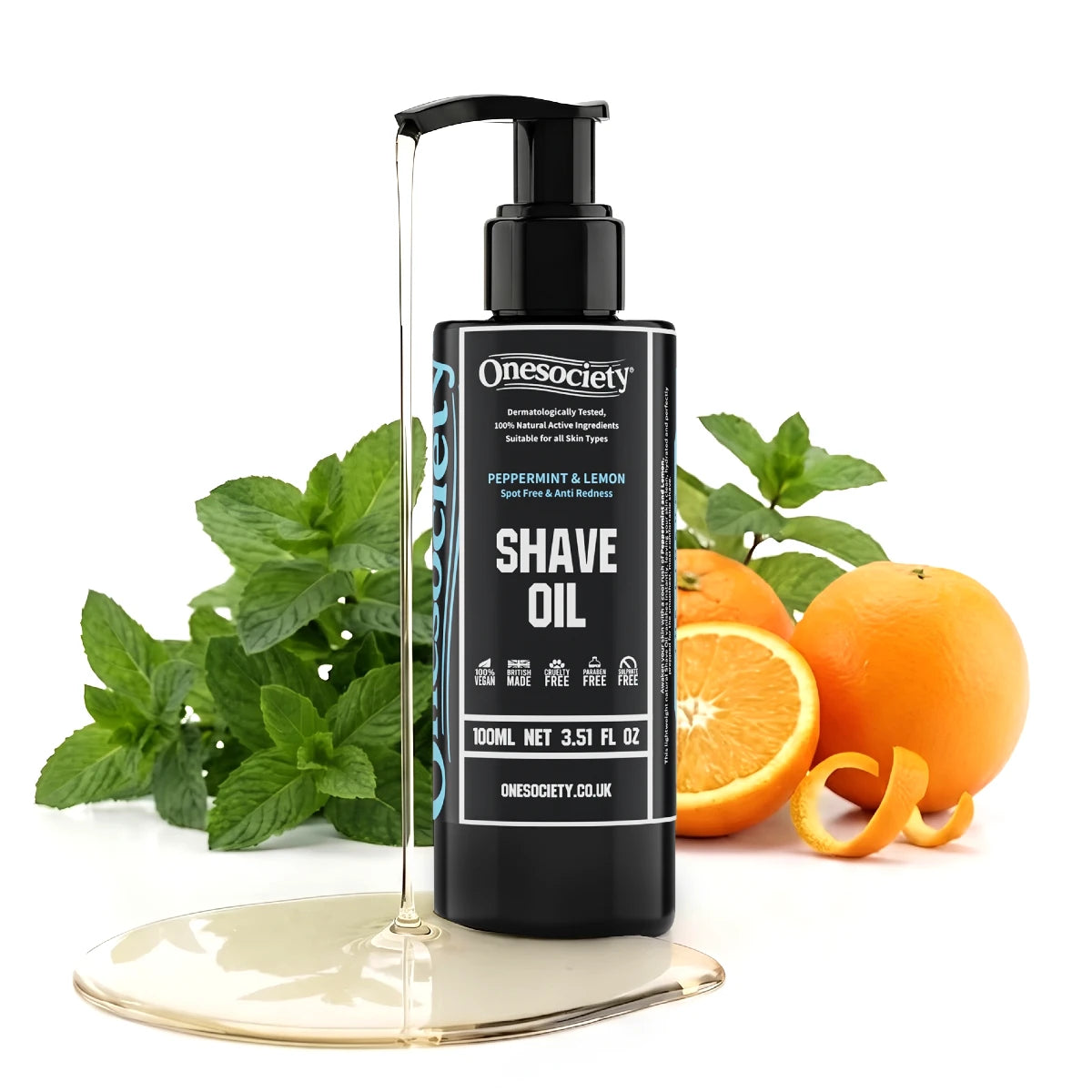 A bottle of Onesociety Peppermint & Lemon Shave Oil stands on a reflective gold base, surrounded by fresh mint leaves, whole oranges, and orange peels on a clean white background.