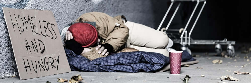 Man sleeping on the street while begging for food.